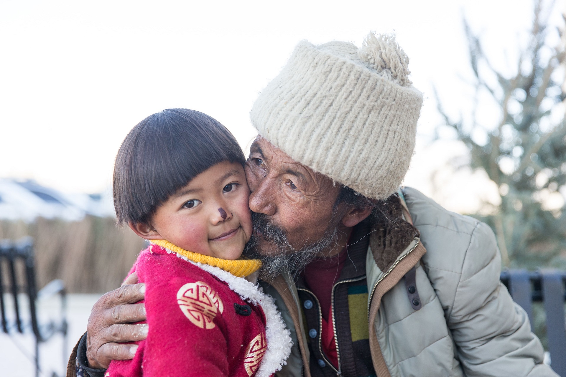 the 5-year-old Tibetan girl is held by her grandfather